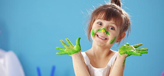 Une jeune fille, les mains dans la peinture verte