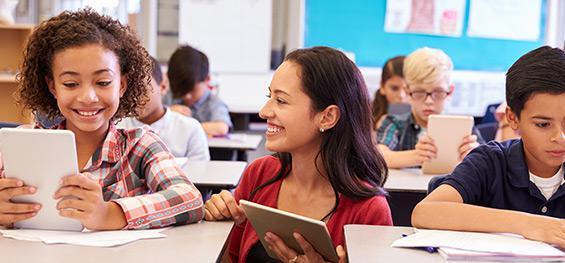 Enseignante souriante à côté de jeunes élèves en classe